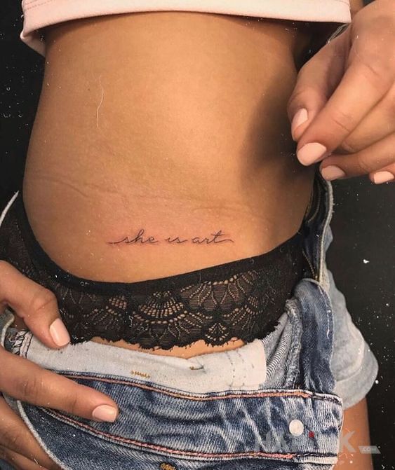 Tattoo Ona jest sztuką in lettering motif and calligraphy style on the ribs