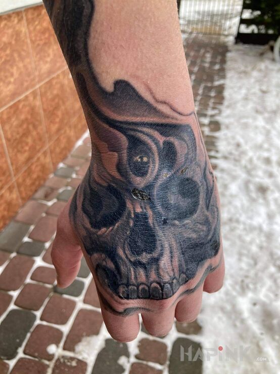 Tattoo Prosze o ocenę in skulls motif and realistic style on the hand