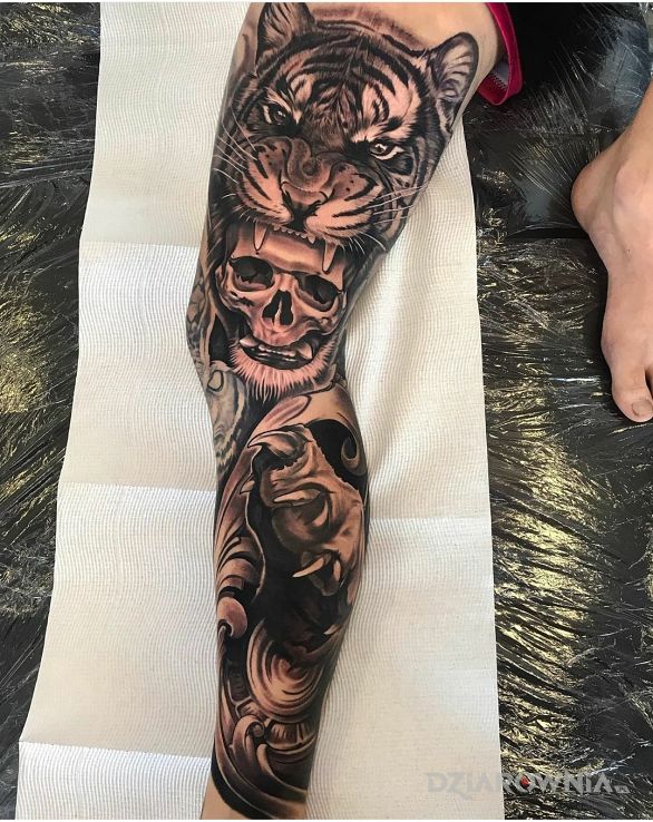 Tatuaż tygrys i jego łapa w motywie czaszki i stylu realistyczne na udzie