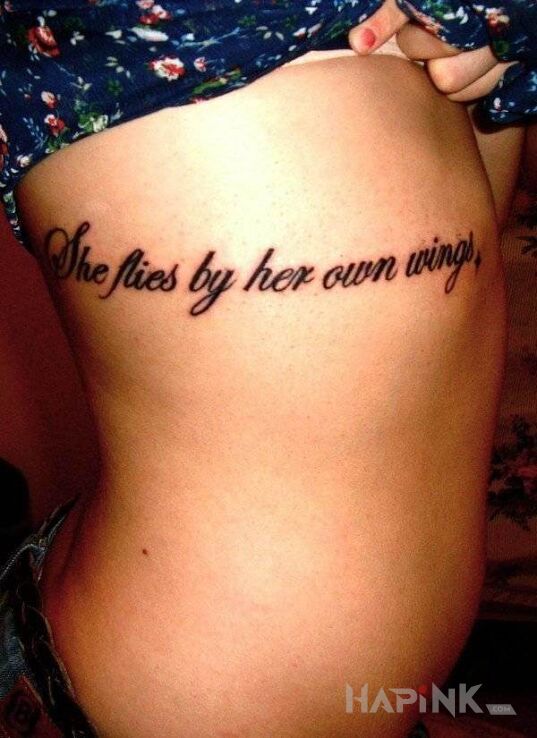 Tattoo She flies by her own wings in lettering motif on the ribs