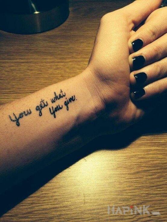 Tattoo You get what you give in lettering motif on the forearm