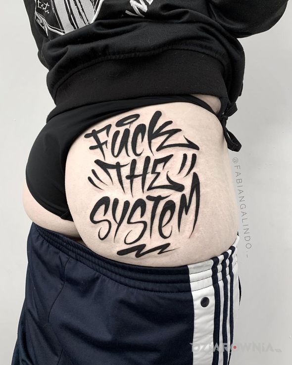 Tatuaż fuck the system w motywie napisy i stylu graffiti na pośladkach