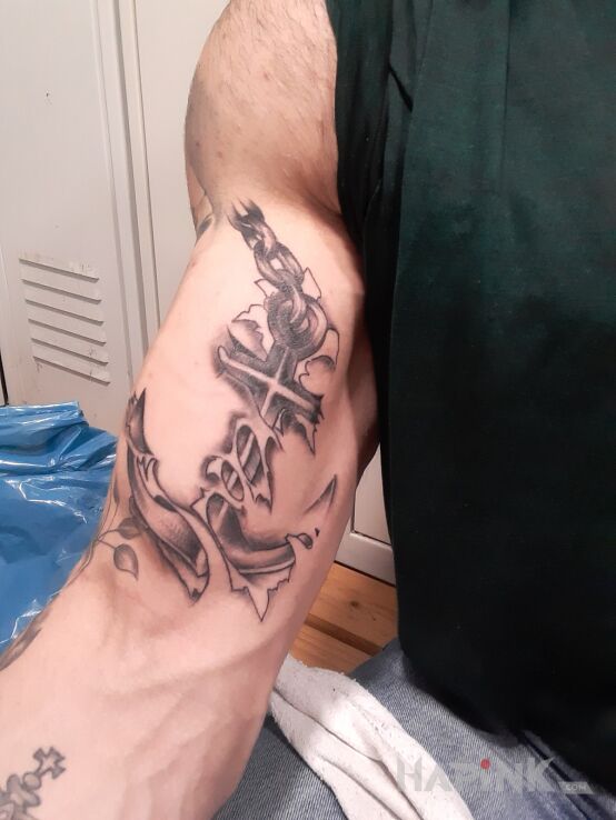 Tattoo Kotwica in black and gray motif and realistic style on the bicep