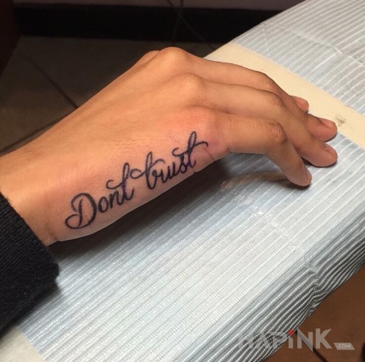 Tattoo Nie ufaj in lettering motif and calligraphy style on the hand