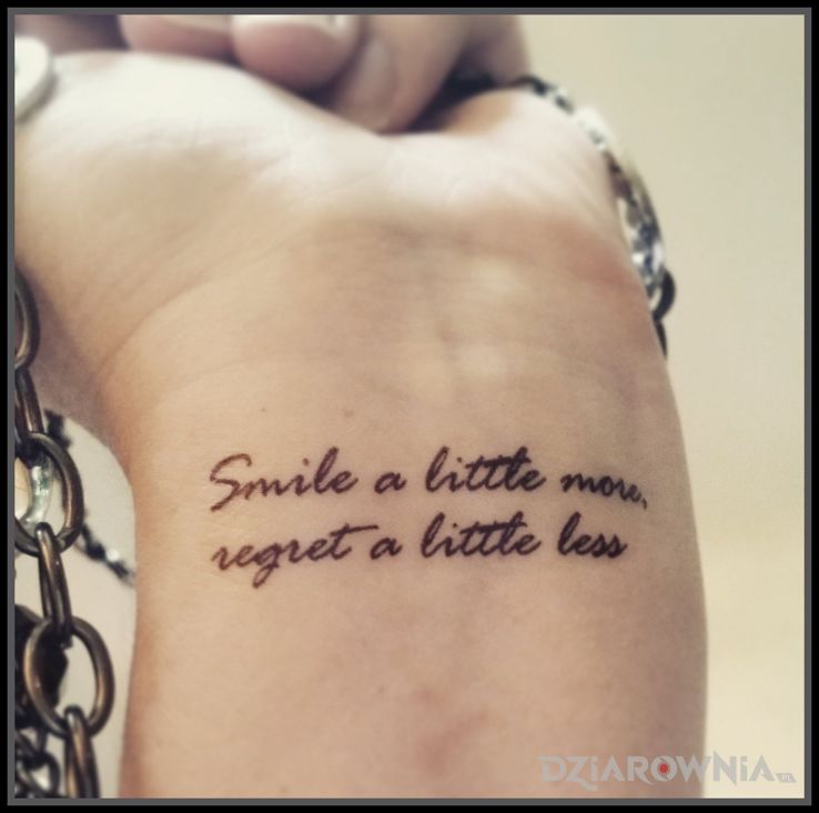 Tatuaż więcej uśmiechu w motywie napisy i stylu kaligrafia na nadgarstku