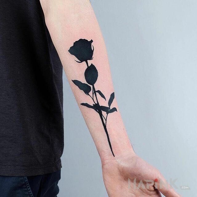 Tattoo Roza jak smola in flowers motif and blackwork / blackout style on the forearm
