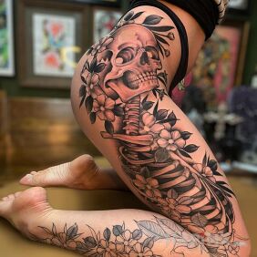 Tattoo Skeleton among flowers on the thigh motif: floral style: realistic