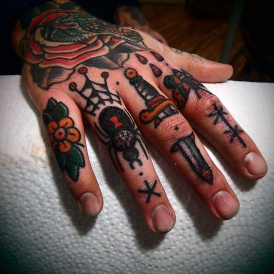 kolorowe tatuaże oldschool na palcach męskiej dłoini