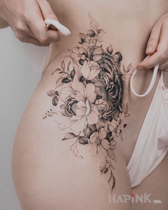Tattoo Tygrysia główka wystająca zza kwiatów in black and gray motif and realistic style on the stomach