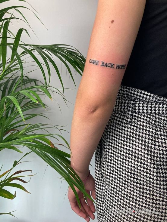 Tatuaż napis come back home w motywie napisy i stylu minimalistyczne na ramieniu