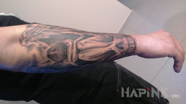 Tattoo Upadły aniołek in skulls motif on the forearm