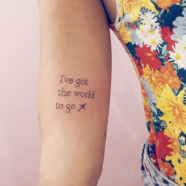 Tattoo Świat do zwiedzenia in lettering motif on the bicep