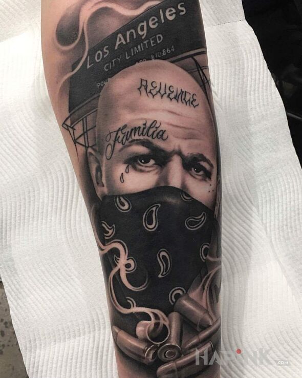 Tattoo Gangus z Los Angeles in black and gray motif and chicano style On the arm