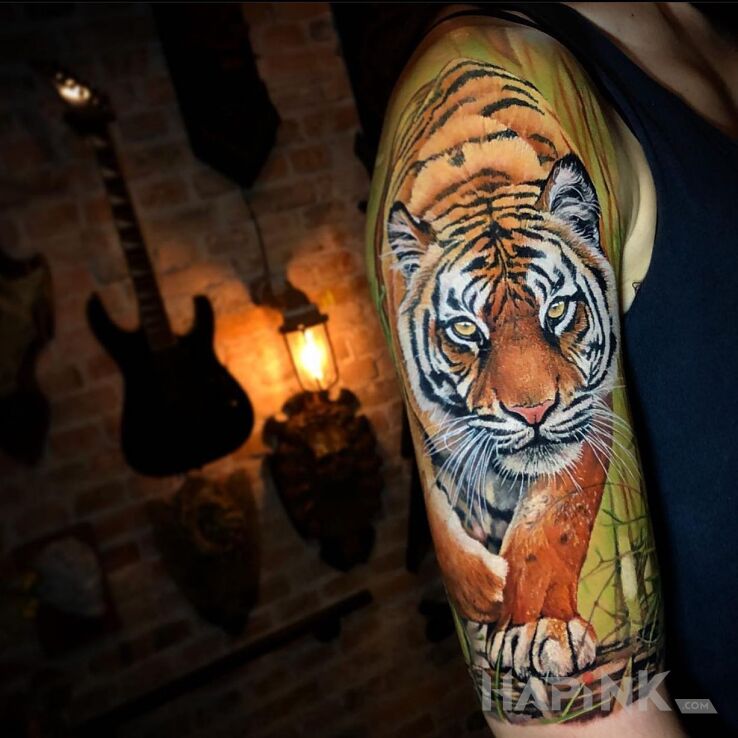 Tattoo Kroczący tygrys in colorful motif and realistic style on the upper arm
