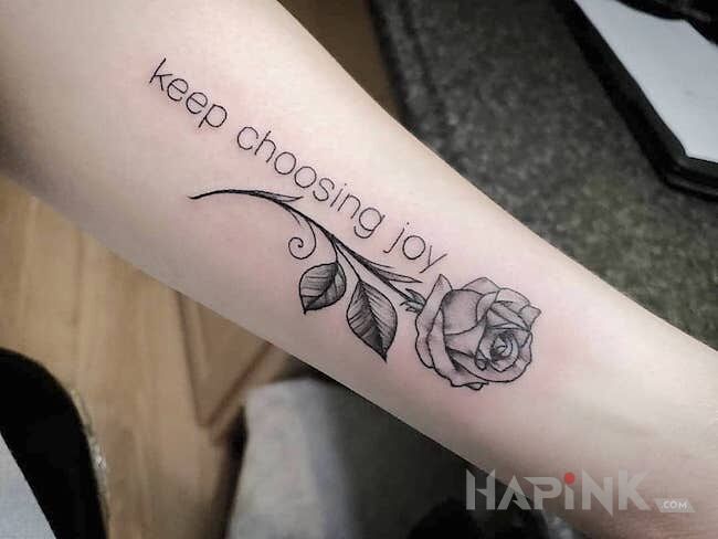 Tattoo Cytat z różą in black and gray motif and graphic / illustrative style On the arm