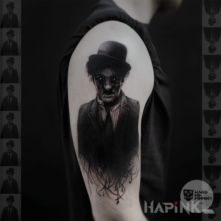 Tattoo Charlie Chaplin in faces motif and blackwork / blackout style on the upper arm