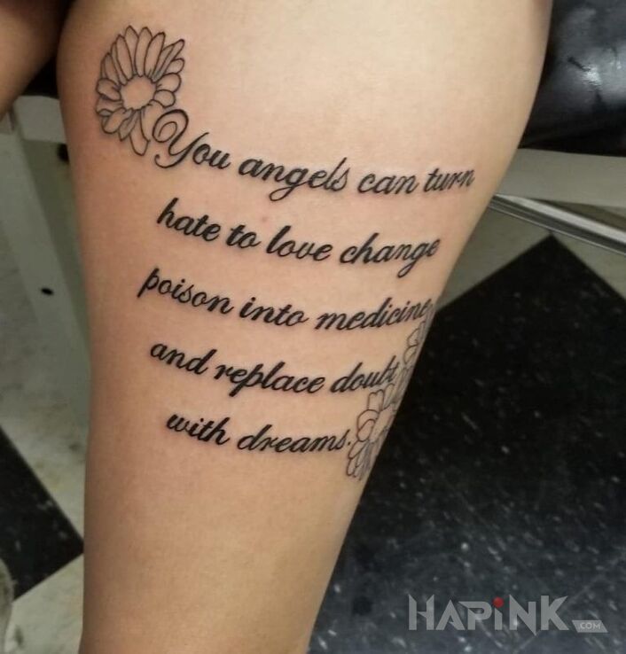 Tattoo Wy aniołowie in flowers motif and calligraphy style on the thigh
