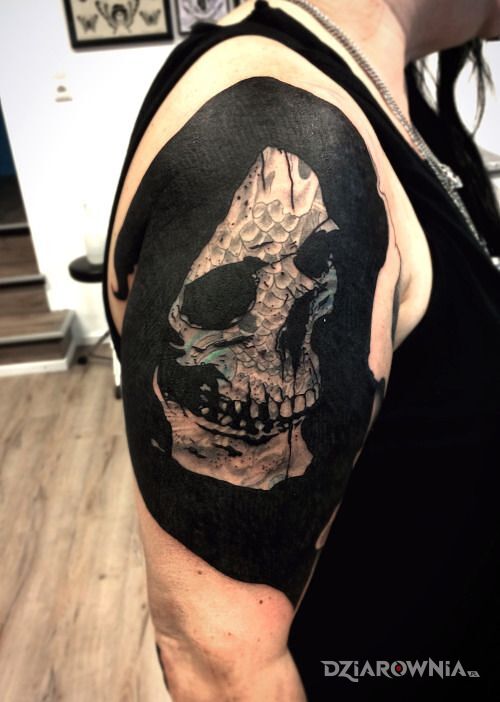 Tatuaż czacha w kapturze w motywie czaszki i stylu blackwork / blackout na ramieniu
