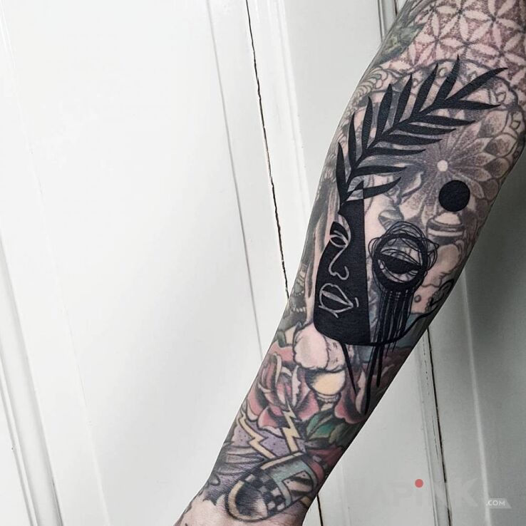 Tattoo Z liściem na głowie in faces motif and abstract style On the arm