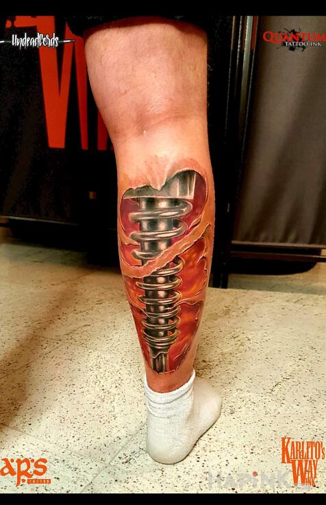 Tattoo Biomechanika in ripped skin motif and biomechanics style on the calf