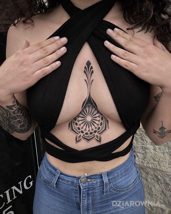 Tatuaż okrągła mandala pomiędzy piersiami w motywie czarno-szare i stylu geometryczne na ręce