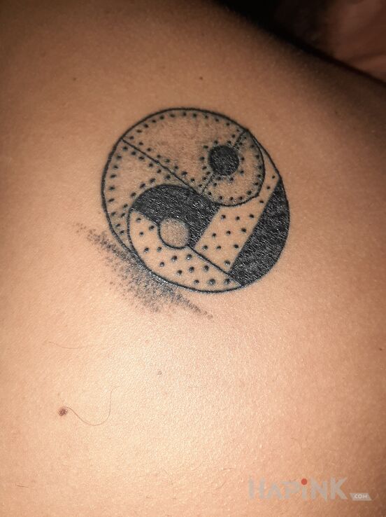 Tattoo Yin yang in black and gray motif and graphic / illustrative style on the shoulder blades