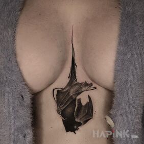 Tattoo Little Bat between the breasts motif: black and gray style: blackwork / blackout