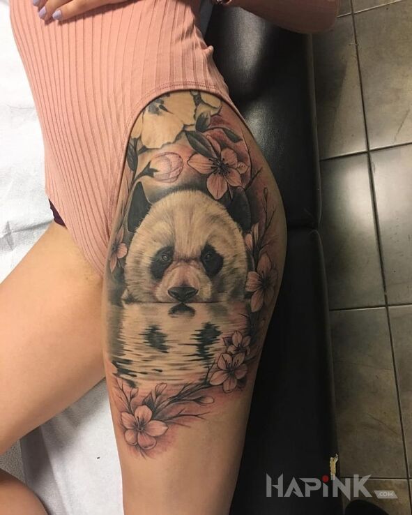 Tattoo Panda in flowers motif and realistic style on the leg