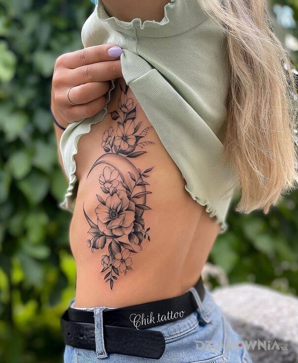 Tatuaż księżyc schowany pomiędzy kwiatami w motywie florystyczne i stylu graficzne / ilustracyjne na żebrach