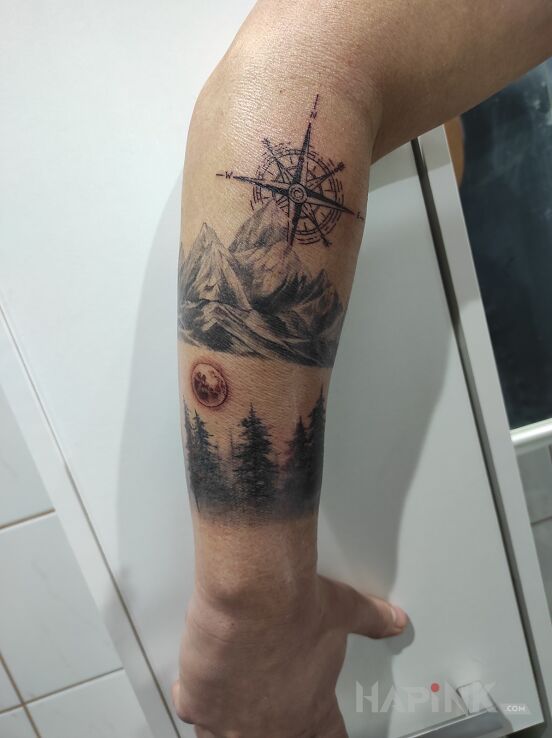 Tattoo Las , góry , róża wiatrów in black and gray motif and graphic / illustrative style on the forearm