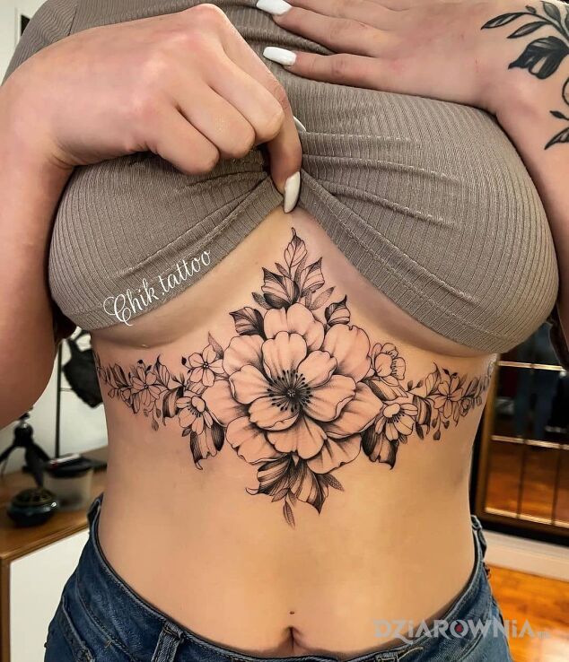 Tatuaż jeden duzy i pare mniejszych kwiatow w motywie czarno-szare i stylu realistyczne pod piersiami (underboob)