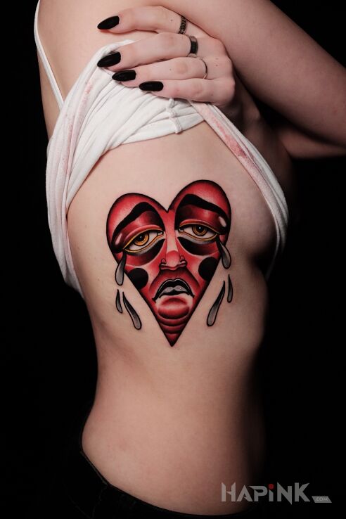 Tattoo Serce / Smutek in faces motif and neo-traditional style on the ribs
