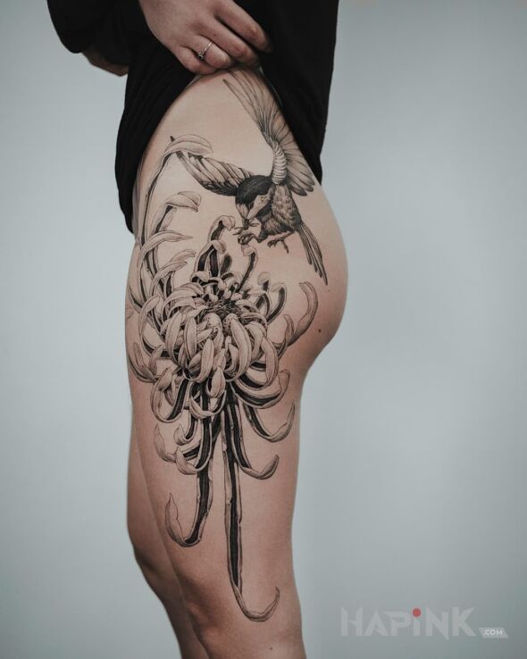 Tattoo Ptak próbujący wylądować na kwiecie in flowers motif and realistic style on the thigh