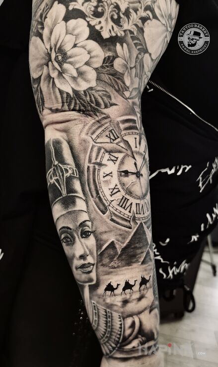 Tattoo Nefretete in flowers motif and realistic style on the upper arm