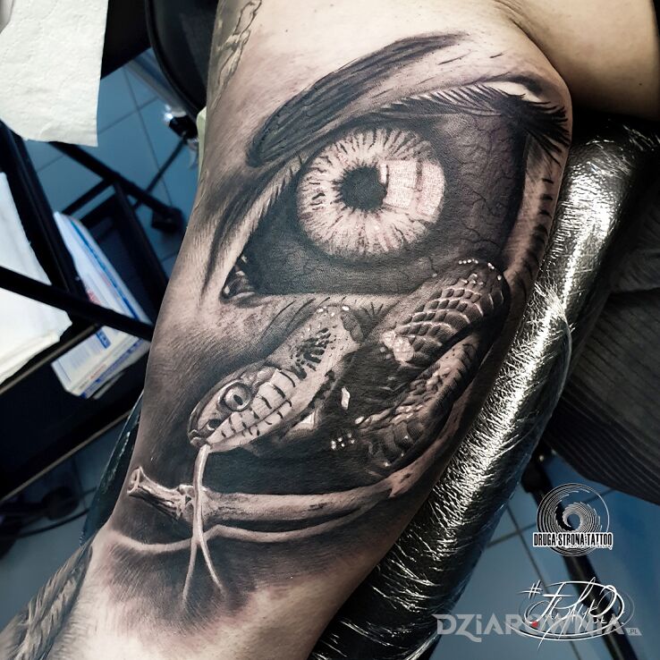 Tatuaż oko wąż i kijek p w motywie mroczne i stylu realistyczne na bicepsie