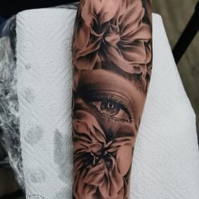 Tattoo Eye hidden in flowers On the arm motif: black and gray style: realistic