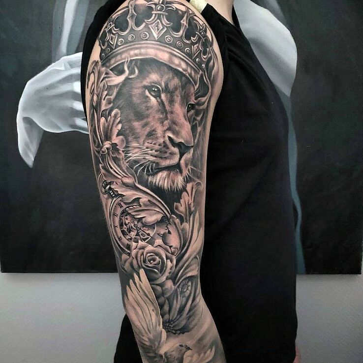 Tatuaż lew w koronie w motywie ornamenty i stylu realistyczne na bicepsie