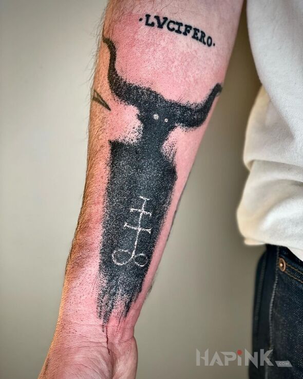 Tattoo Lucifer in dark motif and blackwork / blackout style on the forearm