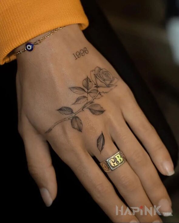 Tattoo Róża i rocznik in black and gray motif and graphic / illustrative style on the hand