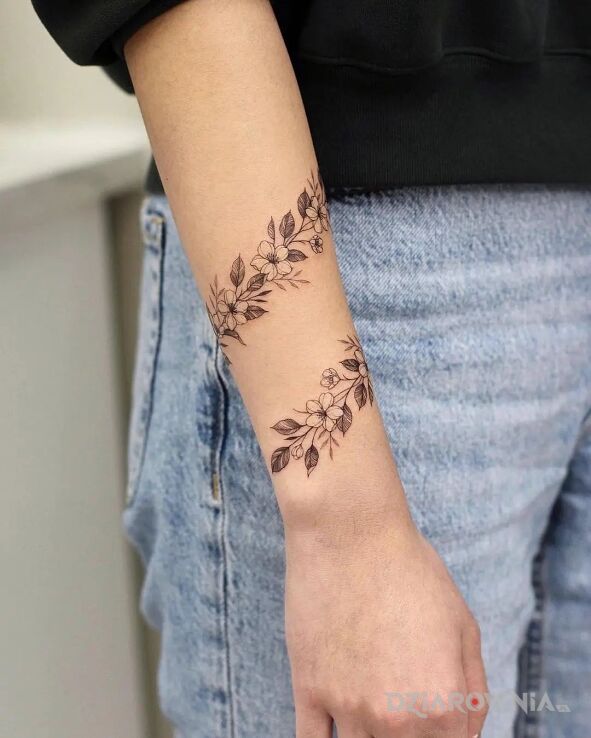 Tatuaż ręka opleciona kwiatami w motywie florystyczne i stylu realistyczne na ręce