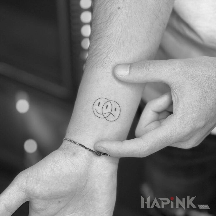 Tattoo Uśmiechnięta i smutna zarazem in other motif and minimalistic style On the arm