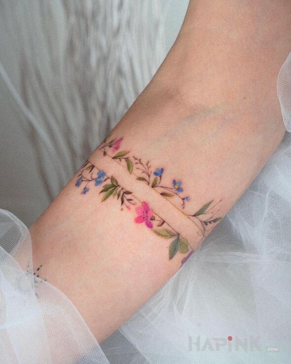 Tattoo Delikatne kwiatki - opaska in flowers motif and realistic style on the forearm