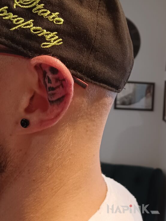 Tattoo Czaszunia in black and gray motif and graphic / illustrative style behind the ear