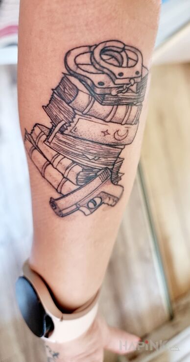 Tattoo Zamiłowanie do kryminałów i romansów in black and gray motif and graphic / illustrative style on the forearm