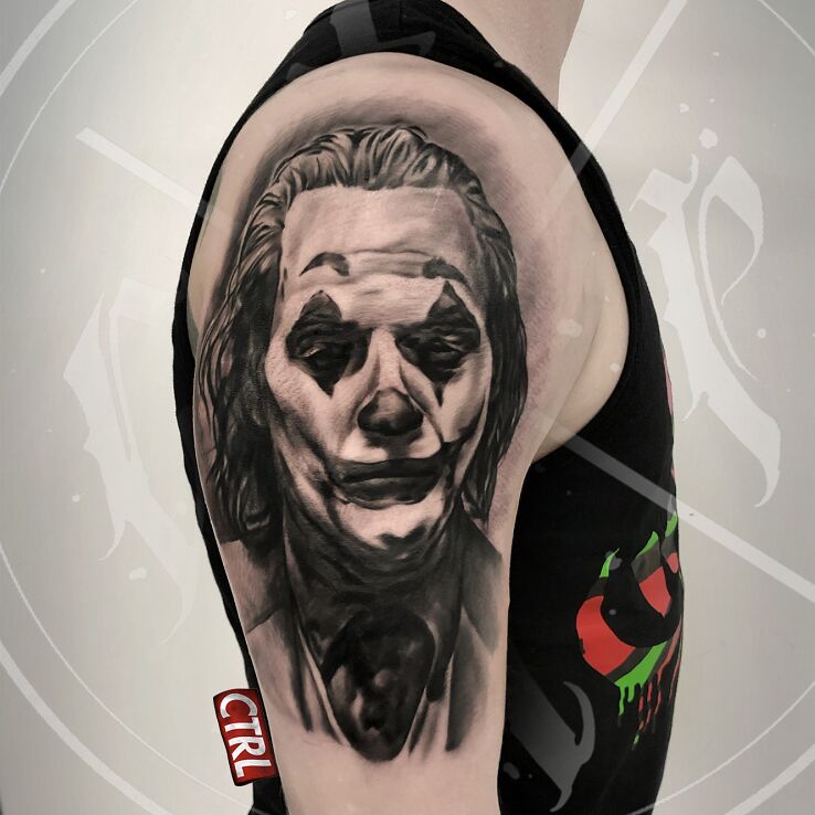 Tatuaż joker w motywie twarze i stylu surrealistyczne na ramieniu
