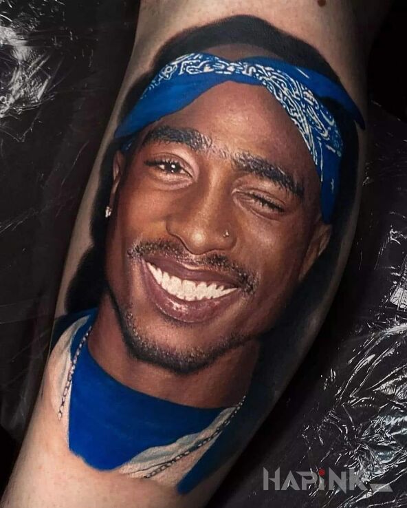 Tattoo Obłędny portret Tupaca in faces motif and realistic style on the bicep