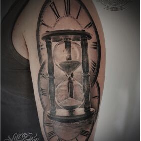 Tattoo Time on the upper arm motif: black and gray style: realistic