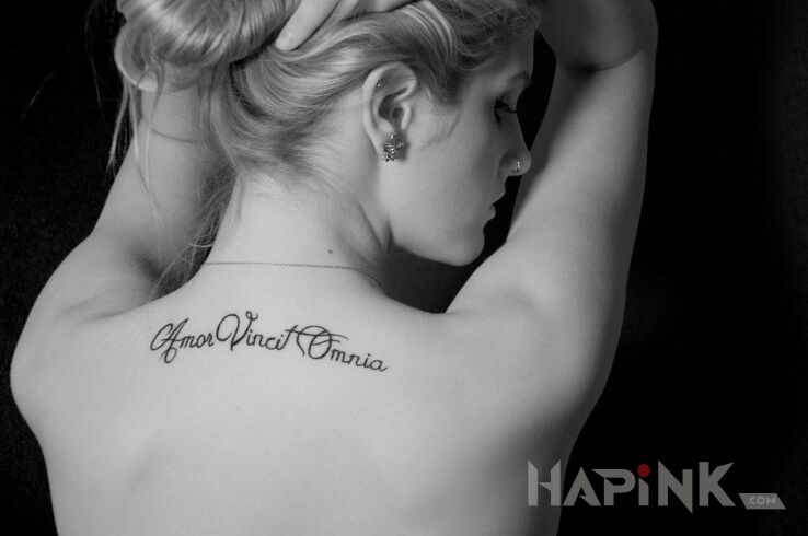 Tattoo Amor vincit omnia in lettering motif on the back
