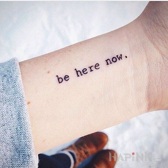 Tattoo Be here now. in lettering motif on the wrist