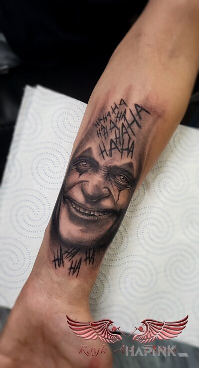 Tattoo Joker in lettering motif and realistic style On the arm